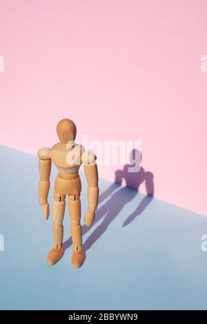 Woodem man Figur auf pinkfarbenem und blauem Hintergrund Stockfoto