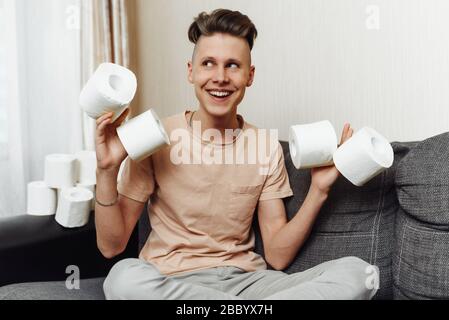 Der junge Kerl hatte während der Pandemie wegen des Coronavirus mit toilettenpapier nach Hause gefüllt. Stockfoto