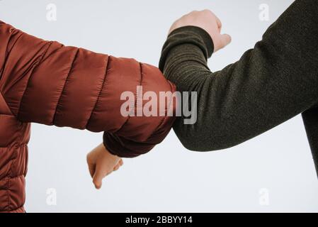 Ellenbogenschlag. Begrüßung, um die Ausbreitung von Coronavirus zu vermeiden. Frauen und Mannfreunde treffen sich. Corona Covid-19 Stockfoto
