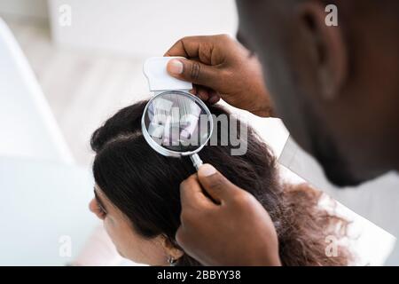 In der Nähe von einem Dermatologen Hand der Patienten die Haare mit Lupe Stockfoto