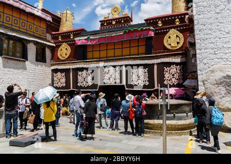 Touristen und Pilger stehen vor dem Jokhang-Tempel und bewundern die Schönheit des berühmten goldfarbenen Dachs. Stockfoto