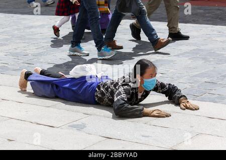 Pilgerin, die auf dem Boden liegt, nachdem sie sich niedergelegt hat. Machen Sie die 'Barkhor Kora', EINE Pilgerreise um das Äußere des Jokhang-Tempels. Stockfoto