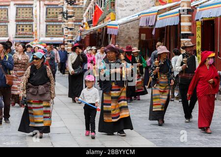 Eine Gruppe tibetischer Pilger, die auf der Barkhor Straße spazieren. Sie halten Gebetskugeln und Handgebeterräder. Im Kreis um den Jokhang-Tempel spazieren. Stockfoto