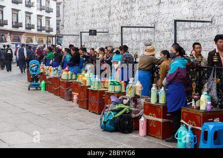 Pilger warten in der Schlange am Eingang des Jokhang-Tempels. Wichtiger Ort des tibetischen buddhismus. Frauen servieren heiße Getränke für die Gläubigen. Stockfoto