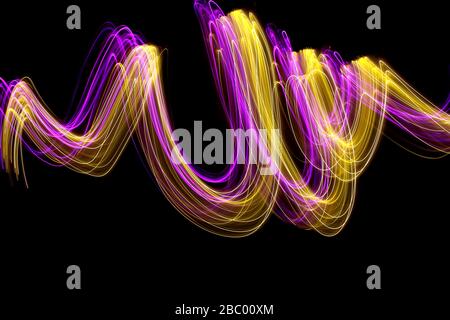 Langbelichtungs-Foto von neonrosa und Gold Farbe in einem abstrakten wirbelnden Linien Muster vor einem schwarzen Hintergrund. Leichte Malerei Fotografie. Stockfoto