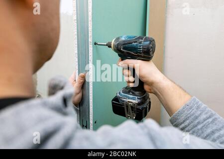 Mann, der feuchtigkeitsbeständige Trockenwandplatten für die Badezimmerschwand installiert Stockfoto