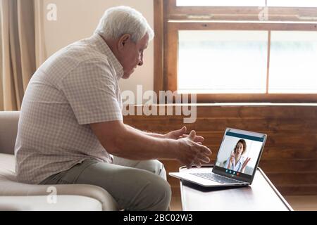Älterer Mann hat einen Videoanruf mit einem Arzt zu Hause Stockfoto