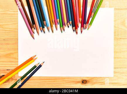 Leeres Papier und bunte Bleistifte auf dem Holztisch. Ansicht von oben. Stockfoto