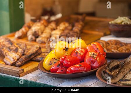 Gegrillte Straßennahrung. Fleisch, Spieße, Paprika, Auberginen und anderes Gemüse im verschwommenen Hintergrund. Außen. Nahaufnahme des horizontalen Fotos. Stockfoto