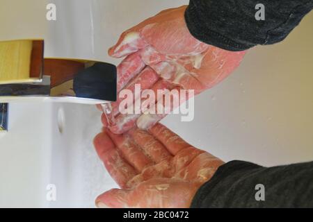 Der Mensch, der seine Hände nach dem Waschen mit Seife mit Wasser ausspült, ist die Hygiene entscheidend, um die Ausbreitung des Coronavirus zu stoppen. Stockfoto