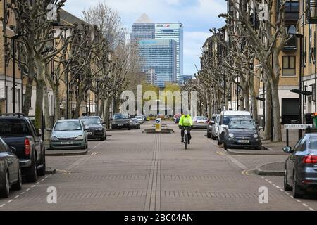 Ein Radfahrer fährt auf leeren Straßen in Sichtweite von Canary Wharf, im Osten Londons, da Großbritannien weiterhin in Sperrungen sitzt, um die Ausbreitung des Coronavirus einzudämmen. Stockfoto