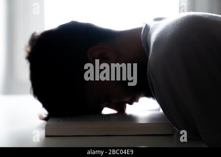 Student müde, mit dem Kopf in einem Buch zu schlafen Stockfoto