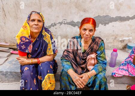 Straßenszene im Distrikt Mahipalpur, einem Vorort in der Nähe des Flughafens von Delhi in Neu-Delhi, Hauptstadt Indiens: Alte Frauen sitzen an der Seite einer Straße Stockfoto