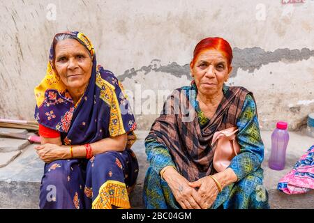 Straßenszene im Distrikt Mahipalpur, einem Vorort in der Nähe des Flughafens von Delhi in Neu-Delhi, Hauptstadt Indiens: Alte Frauen sitzen an der Seite einer Straße Stockfoto