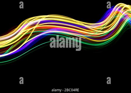 Langbelichtungsfoto von Neon mehrfarbigem Licht in einem abstrakten, geschwungene, parallele Linien Muster vor einem schwarzen Hintergrund. Leichte Malerei Fotografie. Stockfoto