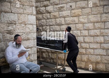 Jerusalem, Israel. April 2020. Mitglieder der Hevrat Kadisha, einer jüdischen Organisation, die Leichen verstorbener Juden für die Bestattung vorbereitet, sorgen für die Aufnahme der Leichen von Israelis, die nach ihrem Tod in Frankreich nach dem Abschluss eines Coronavirus repatriiert wurden. Kredit: Ilia Yefimovich / dpa / Alamy Live News Stockfoto