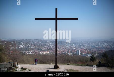Stuttgart, Deutschland. April 2020. Eine Frau steht unter dem Kreuz auf dem Birkenkopf und blickt auf die Innenstadt. Mehr als 15.000.000 Kubikmeter Schutt wurden nach dem zweiten Weltkrieg auf dem Hügel deponiert. Der Berg wird im Volksmund 'Monte Scherbelino' genannt. Kredit: Marijan Murat / dpa / Alamy Live News Stockfoto