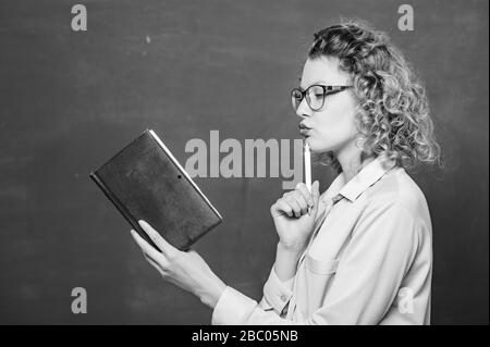 Frau Schullehrerin vor dem Schwarzen Brett. Leidenschaft für Wissen. Lehrer erklären hartes Thema. Lehrer bester Freund der Lernenden. Der Pädiater hält Buch und erklärt Informationen. Bildungskonzept. Stockfoto