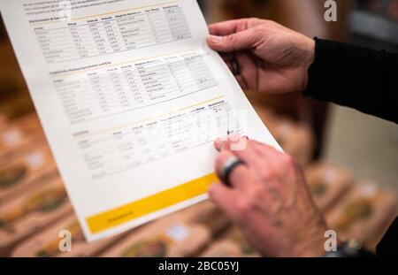 Gangelt Birgden, Deutschland. April 2020. Claudia Karl, Rewe-Mitarbeiterin, sieht sich eine Auftragsliste im Rewe-Supermarkt in Schmiz an. Im Kreis Heinsberg, der besonders vom Corona-Virus betroffen ist, startet die Deutsche Post ein Pilotprojekt zur Bereitstellung grundlegender Dienstleistungen für Risikogruppen, die von der Post mit Lebensmitteln und Haushaltswaren aus dem lokalen Einzelhandel versorgt werden können. Credit: Jonas-Güttler / dpa / Alamy Live News Stockfoto