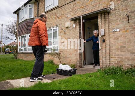 Tony Rosa liefert Lebensmittelpakete vom Enfield Council an Marim Surridge in Enfield, North London. Stockfoto