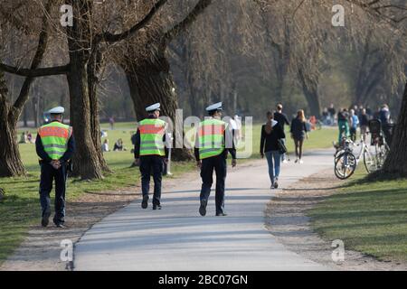 Die Polizei patrouilliert an einem milden Frühlingstag im Englischen Garten und bittet die Anwesenden, sich im Hinblick auf die Infektionsgefahr durch das grassierende Corona-Virus fernzuhalten. [Automatisierte Übersetzung] Stockfoto