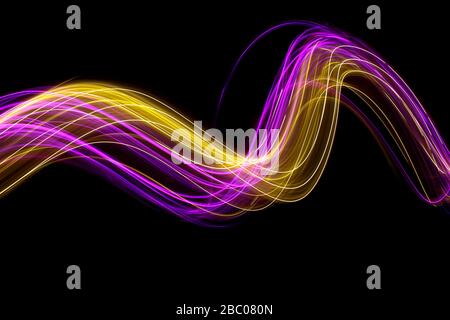 Langbelichtungs-Foto von neonrosa und Gold Farbe in einem abstrakten wirbelnden Linien Muster vor einem schwarzen Hintergrund. Leichte Malerei Fotografie. Stockfoto