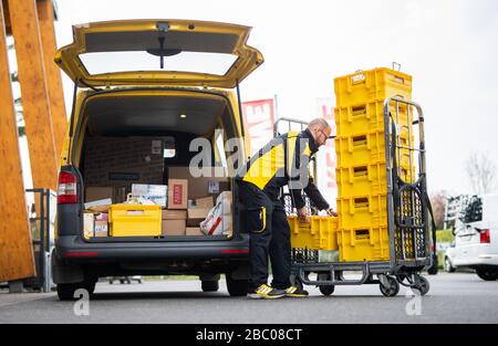 Gangelt Birgden, Deutschland. April 2020. Michael Peltzer, Postbote in Gangelt, packt Lebensmittel in Briefkästen in ein Postauto vor dem Rewe-Supermarkt in Schmiz. Im Kreis Heinsberg, der besonders vom Coronavirus betroffen ist, startet die Deutsche Post ein Pilotprojekt zur Bereitstellung grundlegender Dienstleistungen für Risikogruppen, die von der Post mit Lebensmitteln und Haushaltswaren von den örtlichen Einzelhändlern versorgt werden können. Credit: Jonas-Güttler / dpa / Alamy Live News Stockfoto