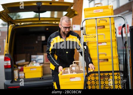 Gangelt Birgden, Deutschland. April 2020. Michael Peltzer, Postbote in Gangelt, packt Lebensmittel in Briefkästen in ein Postauto vor dem Rewe-Supermarkt in Schmiz. Im Kreis Heinsberg, der besonders vom Coronavirus betroffen ist, startet die Deutsche Post ein Pilotprojekt zur Bereitstellung grundlegender Dienstleistungen für Risikogruppen, die von der Post mit Lebensmitteln und Haushaltswaren von den örtlichen Einzelhändlern versorgt werden können. Credit: Jonas-Güttler / dpa / Alamy Live News Stockfoto