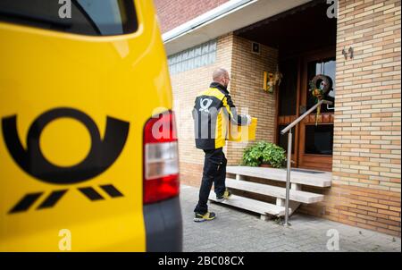 Gangelt Birgden, Deutschland. April 2020. Michael Peltzer, Postbote in Gangelt, transportiert Lebensmittel in Briefkästen zu einem Bewohner in Quarantäne. Im Kreis Heinsberg, der besonders vom Coronavirus betroffen ist, startet die Deutsche Post ein Pilotprojekt zur Bereitstellung von Grundleistungen für Risikogruppen, die von der Deutschen Post mit Lebensmitteln und Haushaltswaren des örtlichen Einzelhandels versorgt werden können. Credit: Jonas-Güttler / dpa / Alamy Live News Stockfoto