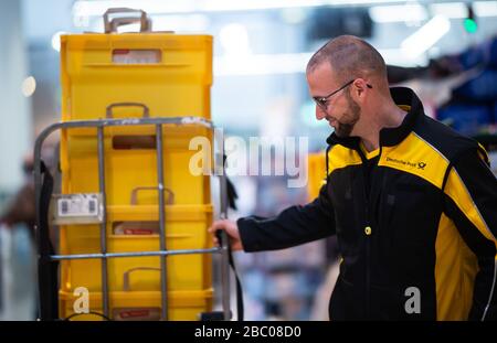 Gangelt Birgden, Deutschland. April 2020. Michael Peltzer, Postbote in Gangelt, fährt Lebensmittel in Briefkästen durch den Supermarkt im Rewe-Supermarkt in Schmiz. Im Kreis Heinsberg, der besonders vom Coronavirus betroffen ist, startet die Deutsche Post ein Pilotprojekt zur Bereitstellung grundlegender Dienstleistungen für Risikogruppen, die von der Post mit Lebensmitteln und Haushaltswaren aus dem lokalen Einzelhandel versorgt werden können. Credit: Jonas-Güttler / dpa / Alamy Live News Stockfoto