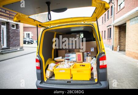 Gangelt Birgden, Deutschland. April 2020. Lebensmittel in Postkästen liegen zwischen Paketen in einem Postbus. Im Kreis Heinsberg, der besonders vom Coronavirus betroffen ist, startet die Deutsche Post ein Pilotprojekt zur Bereitstellung von Grundleistungen für Risikogruppen, die von der Deutschen Post mit Lebensmitteln und Haushaltswaren des örtlichen Einzelhandels versorgt werden können. Credit: Jonas-Güttler / dpa / Alamy Live News Stockfoto