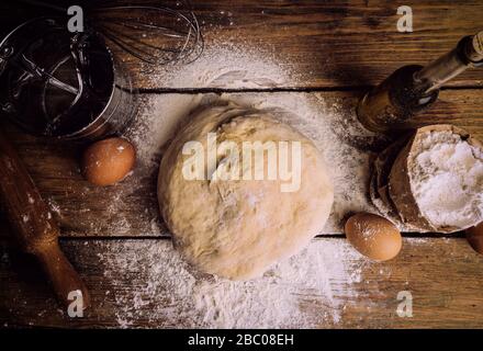 Pizza Teig Kochen in der Hausküche. Hausgemachter Teig für Brot, Pizza, Gebäck und Brötchen. Teige (Mehl, Eier, Butter) auf einem Holzrost Stockfoto