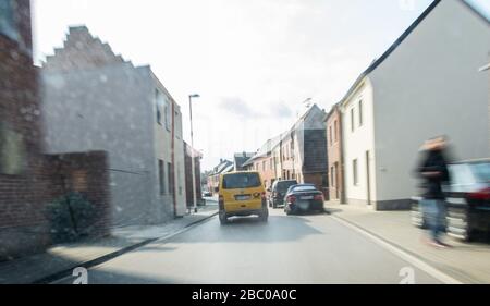 Gangelt Birgden, Deutschland. April 2020. Ein Auto der Deutschen Post fährt durch die Stadt. Im Kreis Heinsberg, der besonders vom Coronavirus betroffen ist, startet die Deutsche Post ein Pilotprojekt zur Bereitstellung von Grundleistungen für Risikogruppen, die von der Deutschen Post mit Lebensmitteln und Haushaltswaren des örtlichen Einzelhandels versorgt werden können. Credit: Jonas-Güttler / dpa / Alamy Live News Stockfoto