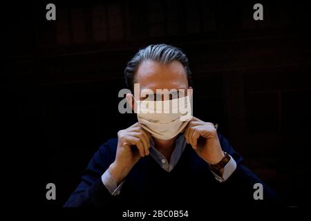 Berlin, Deutschland. März 2020. Jan Scheper-Stuke, Geschäftsführer des Berliner Tie-Herstellers Auerbach, zeigt in der Krawattenwerkstatt eine weiße Mundnasenmaske aus Stoff. Seit vergangener Woche werden verschiedene Modelle von Mundnasenmasken aus verschiedenen Stoffen vom Krawattenhersteller angeboten. Credit: Carsten Koall / dpa / Alamy Live News Stockfoto