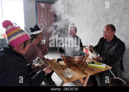 (200402) -- NANNING, 2. April 2020 (Xinhua) -- der Villager Li Zhiming (1. R) und seine Familie haben ein Essen in ihrem neuen Zuhause in einem Umsiedlungsort zur Armutsbekämpfung im Nandan County im südchinesischen Autonomen Gebiet Guangxi Zhuang, 4. Februar 2018. Die Autonome Region Guangxi Zhuang, eine Schlüsselregion in Chinas Anti-Armut-Bemühungen, hat dazu geführt, dass etwa 710.000 Menschen, die während der 13. Fünfjährigen Planungsperiode (2016-2020) aus unwirtlichen Gebieten umgesiedelt wurden, als Schlüsselkampf gegen Armut identifiziert und Akten eingerichtet wurden. Das Umzugsprogramm wurde Ende letzten Jahres abgeschlossen. Viele Menschen wurden bewegt Stockfoto