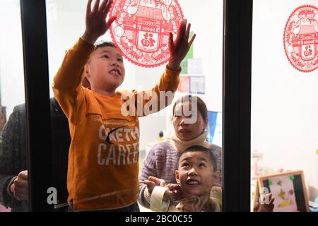 (200402) -- NANNING, 2. April 2020 (Xinhua) -- Resident Hu Hongjun (R, Back) und ihre Familie fügen eine Papierschneidearbeit an ihrem neuen Wohnort im Xingye County im südchinesischen Autonomen Gebiet Guangxi Zhuang, 20. Januar 2020, ein. Die Autonome Region Guangxi Zhuang, eine Schlüsselregion in Chinas Anti-Armut-Bemühungen, hat dazu geführt, dass etwa 710.000 Menschen, die während der 13. Fünfjährigen Planungsperiode (2016-2020) aus unwirtlichen Gebieten umgesiedelt wurden, als Schlüsselkampf gegen Armut identifiziert und Akten eingerichtet wurden. Das Umzugsprogramm wurde Ende letzten Jahres abgeschlossen. Viele Menschen wurden aus dem Umweltschutz entfernt Stockfoto