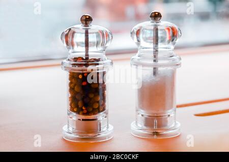 Glassalz- und Pfefferschäcker stehen auf einem Tisch Stockfoto