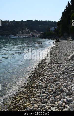 Kieselstrand an der Lakka Bay. Ein kleines touristisches Dorf auf der Spitze der Insel Paxos. Griechische Insel. Stockfoto