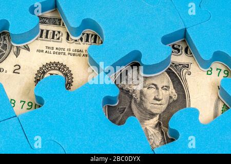 US-Dollar-Währung unter Puzzle versteckt. Finanz- oder Wirtschaftskonzept Stockfoto