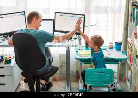 Vater mit Kind versucht, während der Quarantäne von zu Hause aus zu arbeiten. Bleiben Sie zu Hause, arbeiten Sie von zu Hause aus bei einer Coronavirus Pandemie Stockfoto