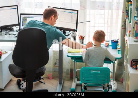 Vater mit Kind versucht, während der Quarantäne von zu Hause aus zu arbeiten. Bleiben Sie zu Hause, arbeiten Sie von zu Hause aus bei einer Coronavirus Pandemie Stockfoto