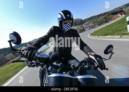 Amtzell, Deutschland. April 2020. Ein Motorradfahrer fährt auf einer kurvenreichen Straße in Richtung Württembergisches Allgäuer. Viele Motorradfans werden ihre Fahrräder im April aus dem Winterschlaf bringen und freuen sich auf die kommende Motorradsaison. Kredit: Felix Kästle / dpa / Alamy Live News Stockfoto