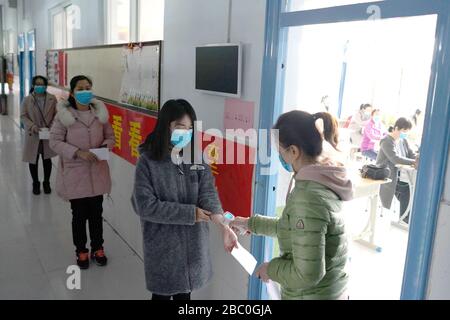 Xingtai, Chinas Provinz Hebei. April 2020. Lehrer, die als Schüler auftreten, nehmen vor dem Eintritt in den Unterricht während einer Probe in einer Schule in Xingtai City, der Provinz Hebei in Nordchina, am 2. April 2020, eine Temperaturkontrolle vor. Schulen in Xingtai City haben Proben für die Wiederaufnahme der Klasse von Schülern in ihrem letzten Jahr der Senior- und Juniorhochschulen durchgeführt, um eine sichere und geordnete Schuleröffnung mit rigiden epidemischen Präventionsmaßnahmen sicherzustellen. Kredit: Mou Yu/Xinhua/Alamy Live News Stockfoto