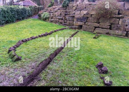 Installation eines Ablaufgrabens in einem Gartenrasen, Stockfoto