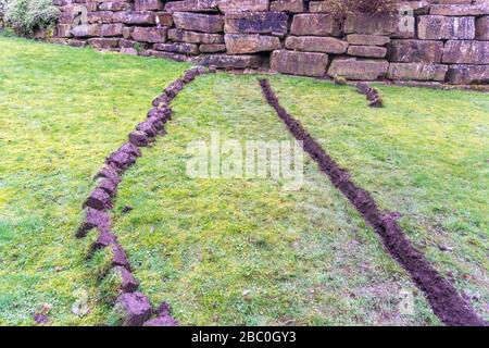 Installation eines Ablaufgrabens in einem Gartenrasen, Stockfoto