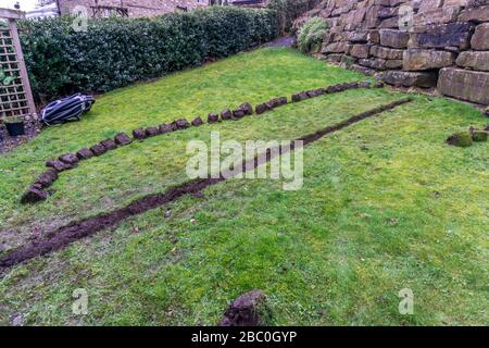 Installation eines Ablaufgrabens in einem Gartenrasen, Stockfoto