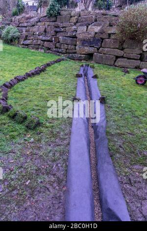 Installation eines Ablaufgrabens in einem Gartenrasen, Stockfoto