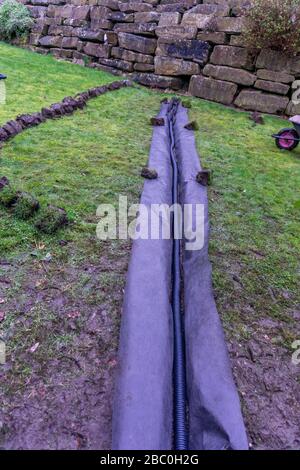 Installation eines Ablaufgrabens in einem Gartenrasen, Stockfoto