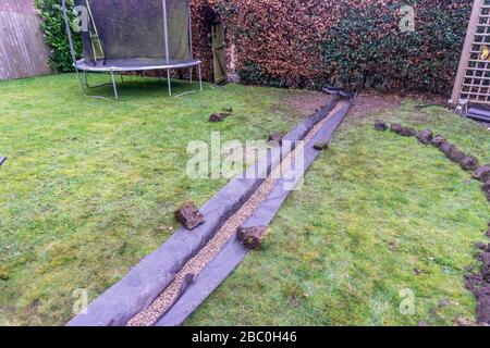 Installation eines Ablaufgrabens in einem Gartenrasen, Stockfoto