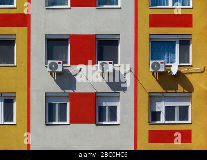 Klimaanlagenwand installierte Kondensatoreinheiten. Wohnfenster am Apartmentgebäude Außenwand- oder Fassadendetails. Bunte Stuck-Isolierung Stockfoto